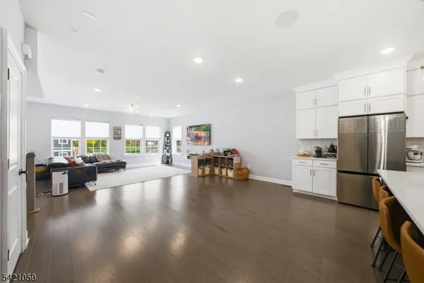 a kitchen with stainless steel appliances a refrigerator a stove a dining table and chairs with wooden floor