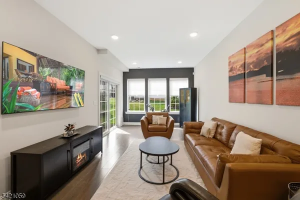 a living room with furniture a flat screen tv with wooden floor and windows
