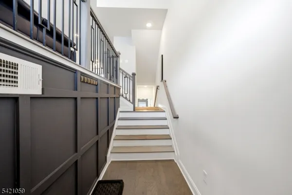 a view of staircase with lots of frames on wall and wooden floor