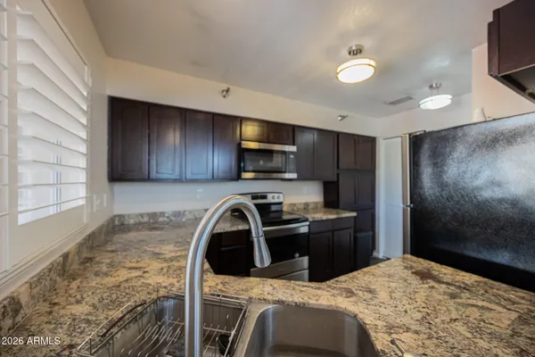 a kitchen with granite countertop a stove a sink and a microwave
