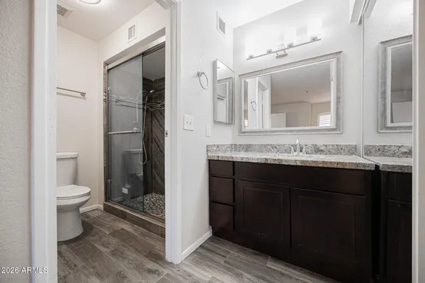 a bathroom with a granite countertop sink toilet and mirror