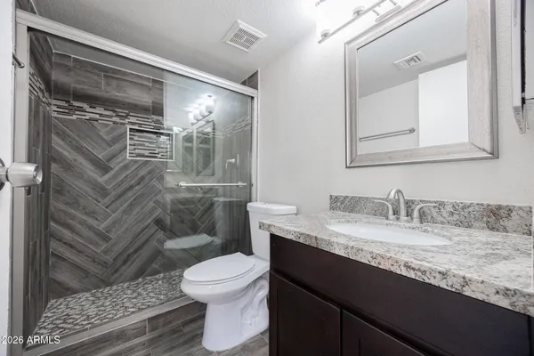 a bathroom with a granite countertop sink toilet and shower