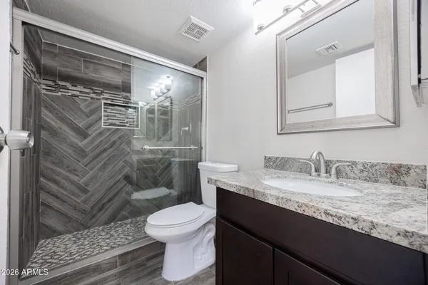a bathroom with a granite countertop sink toilet and shower