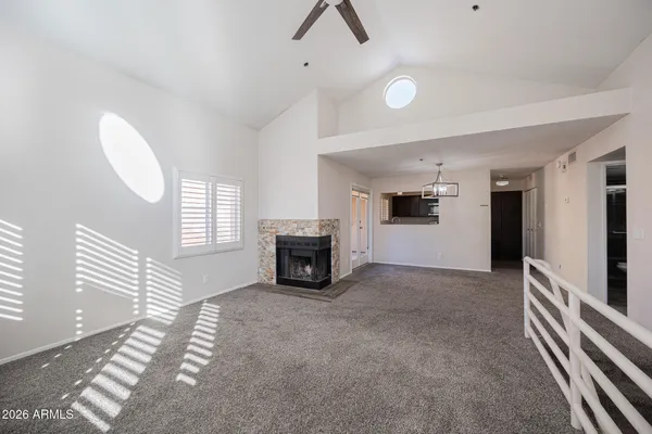 an empty room with windows fireplace and fans
