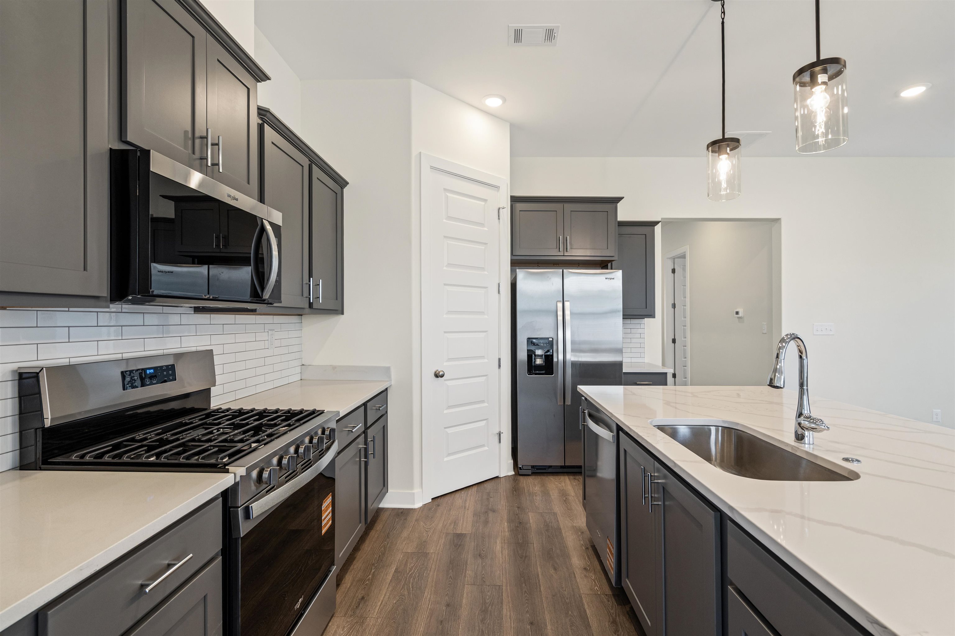 5666 Pleasant Pk Place Arlington, TN 38002 - Photo 15 of 27 Modern kitchen featuring dark cabinetry, stainless steel appliances, a subway tile backsplash, light-toned countertops, and wood-finish flooring