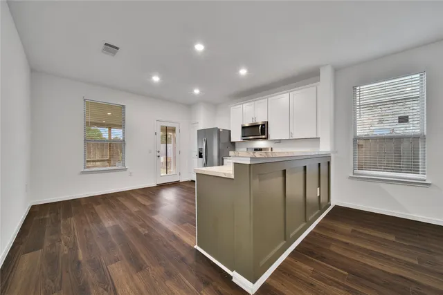 a kitchen with stainless steel appliances granite countertop a refrigerator a stove and a wooden floors