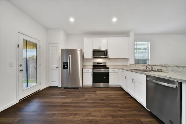 a kitchen with granite countertop a refrigerator and a stove top oven