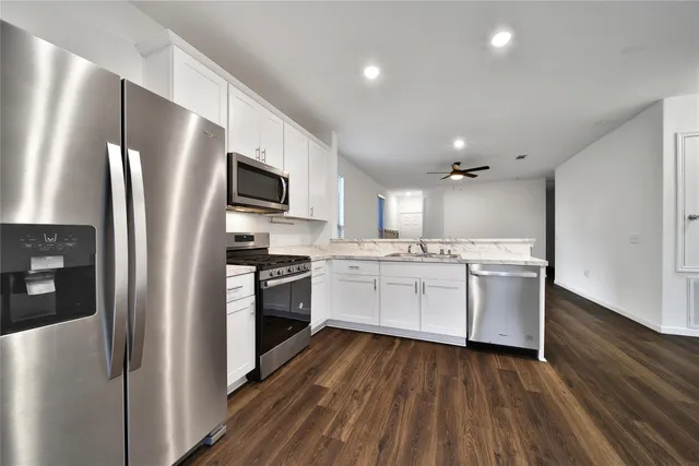 a kitchen with white cabinets stainless steel appliances and a refrigerator