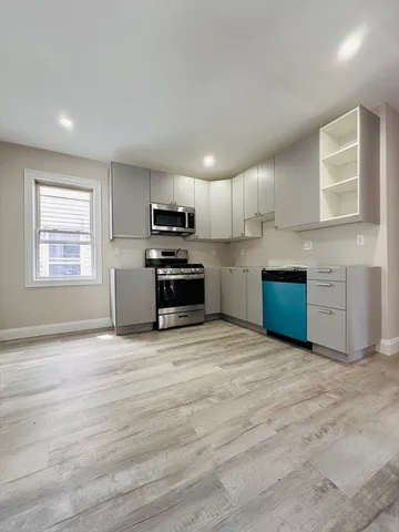 a view of kitchen with stainless steel appliances granite countertop a stove top oven a sink dishwasher and a refrigerator with wooden floor