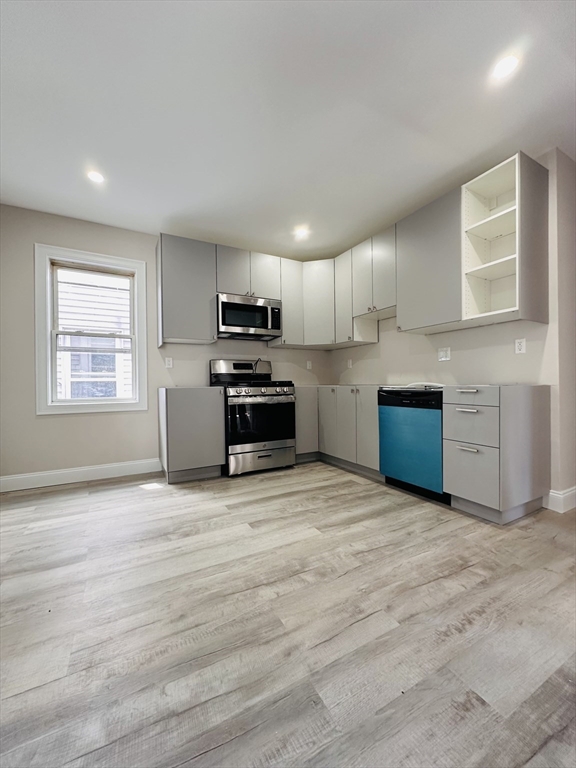 a view of kitchen with stainless steel appliances granite countertop a stove top oven a sink dishwasher and a refrigerator with wooden floor