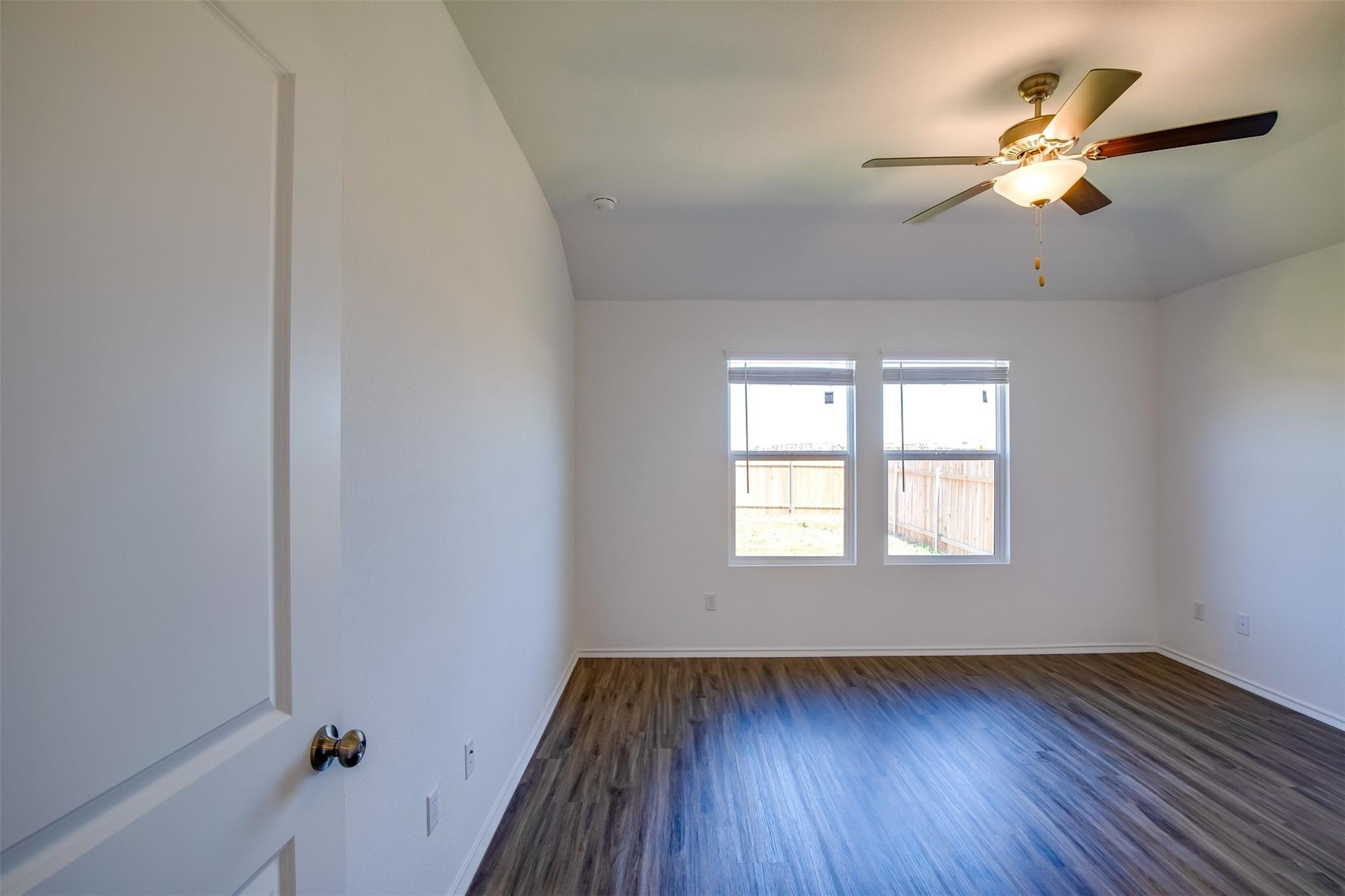 614 Milliner Loop Hutto, TX 78634 - Photo 16 of 25 Natural light filters into this bedroom, featuring sleek hardwood flooring and a functional ceiling fan.