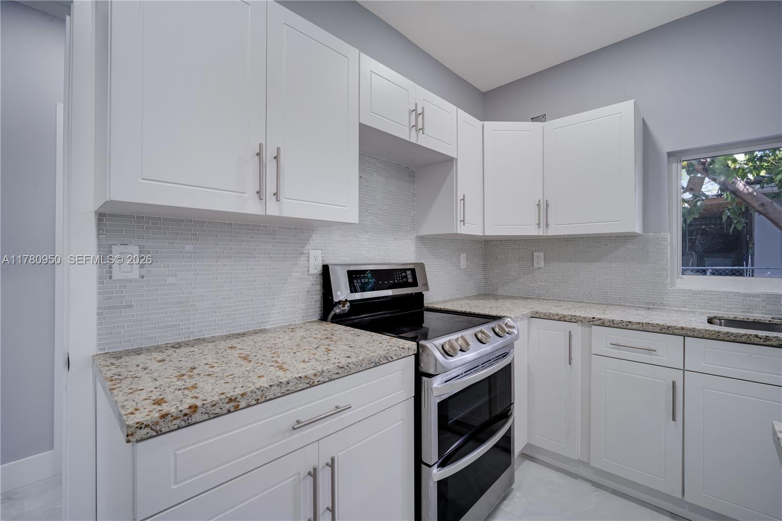 1114 Southwest 13th Court Miami, FL 33135 - Photo 11 of 43 a kitchen with granite countertop white cabinets and white appliances