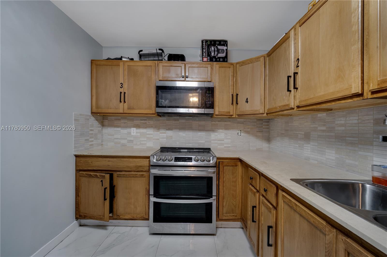 1114 Southwest 13th Court Miami, FL 33135 - Photo 34 of 43 a kitchen with stainless steel appliances granite countertop a stove and a microwave