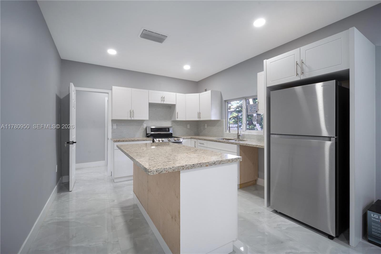 1114 Southwest 13th Court Miami, FL 33135 - Photo 10 of 43 a kitchen with kitchen island a refrigerator a sink and cabinets