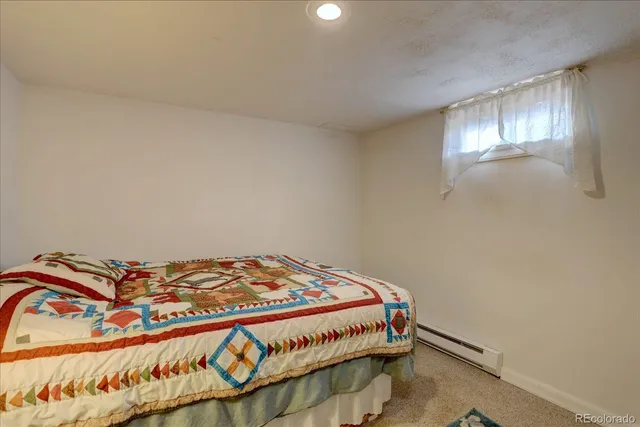 a bedroom with a bed and a lamp on dresser