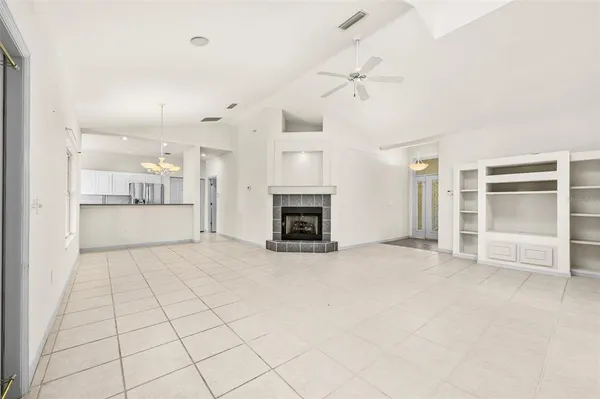 an empty room with fireplace cabinet and windows