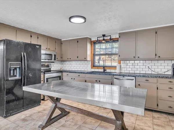 a kitchen with granite countertop a table chairs microwave and cabinets