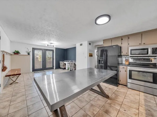 a kitchen with stainless steel appliances granite countertop a sink a stove a refrigerator white cabinets and couches with wooden floor