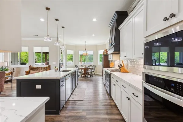 a kitchen with stainless steel appliances granite countertop a sink a stove a dining table and chairs