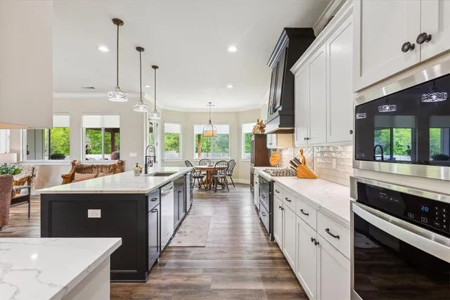a kitchen with stainless steel appliances granite countertop a sink a stove a dining table and chairs