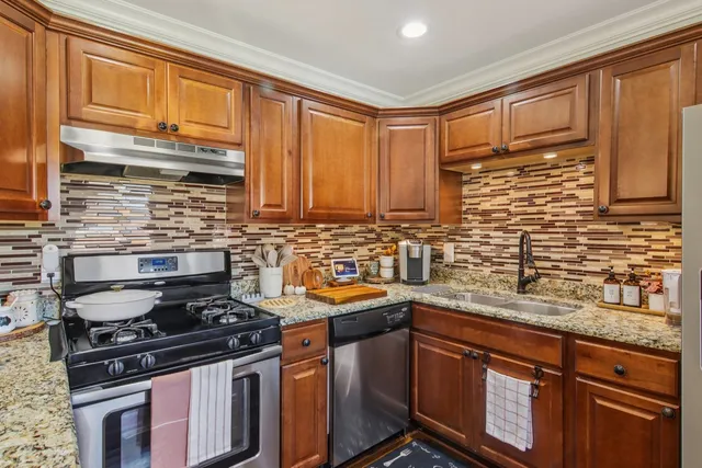 a kitchen with stainless steel appliances granite countertop a sink stove and cabinets