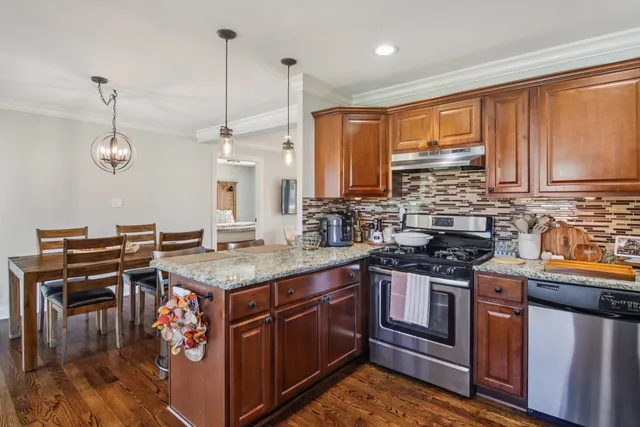 a kitchen with stainless steel appliances granite countertop a stove a sink dishwasher and cabinets with wooden floor