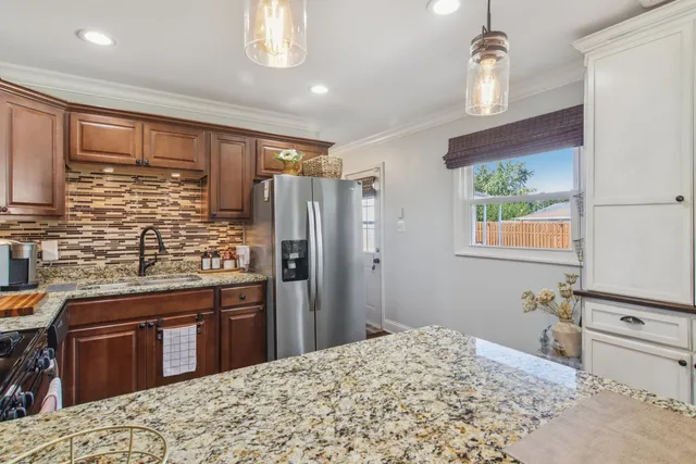 a kitchen with stainless steel appliances kitchen island granite countertop a refrigerator and wooden cabinets