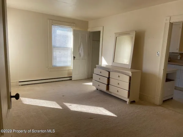 a view of empty room with window and wooden floor