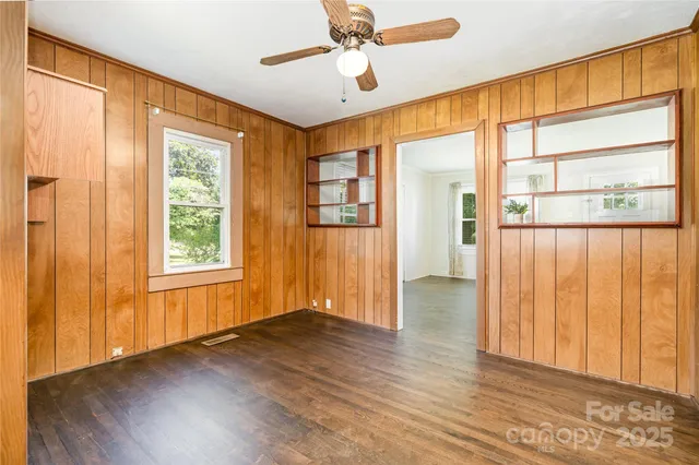 a view of empty room with wooden floor and fan