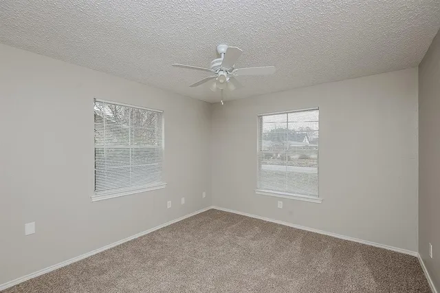 an empty room with a window and a fan