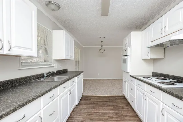 a kitchen with granite countertop a sink stove and cabinets