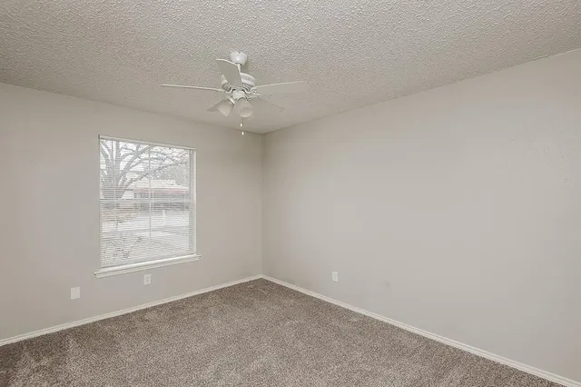 an empty room with windows and fan