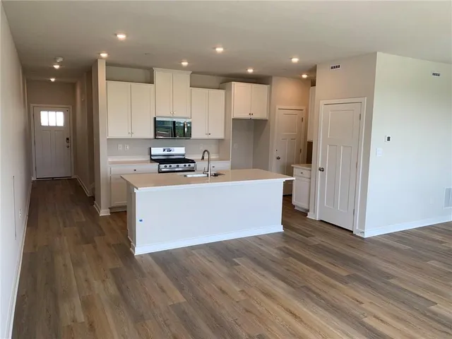 a large kitchen with kitchen island a stove a refrigerator a sink dishwasher and a oven with wooden floor