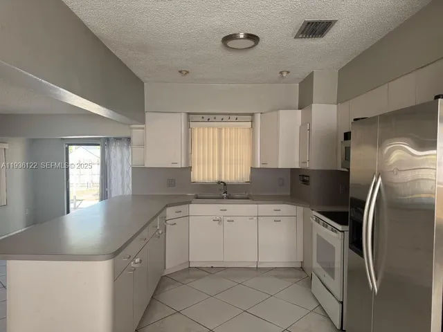 a kitchen with a sink a refrigerator and window