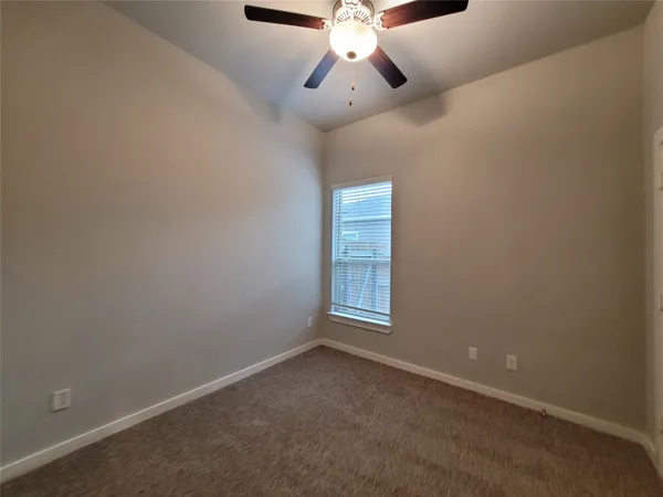 an empty room with chandelier fan and windows
