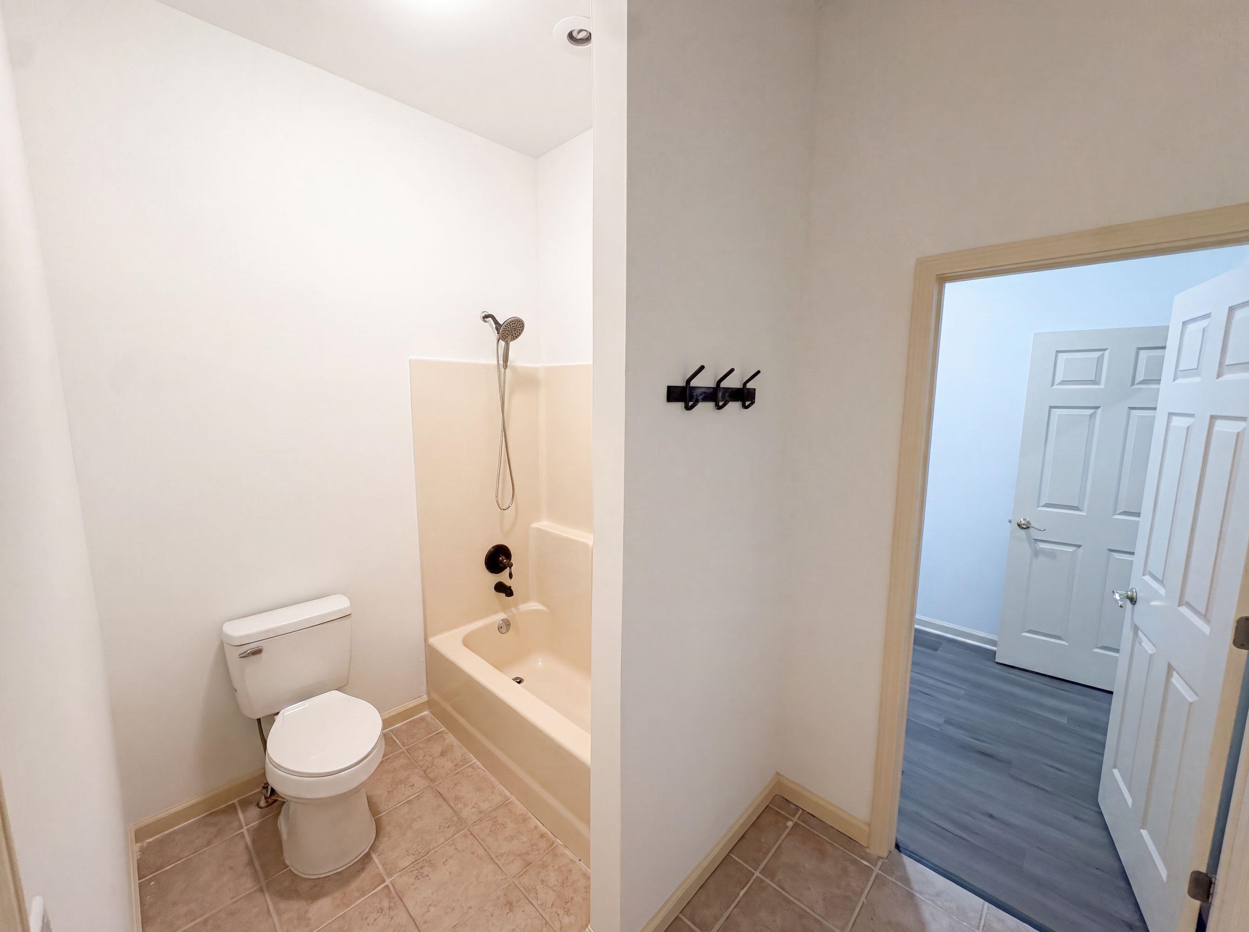 9424 Gotten Road Germantown, TN 38139 - Photo 17 of 27 Full bathroom featuring a tub/shower combination with dark bronze fixtures, a white toilet, and tile flooring