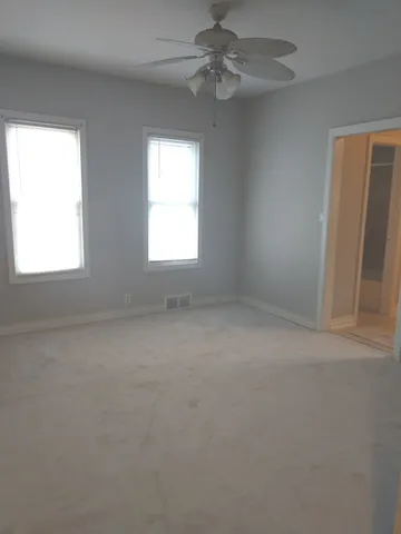 an empty room with a window and a fan