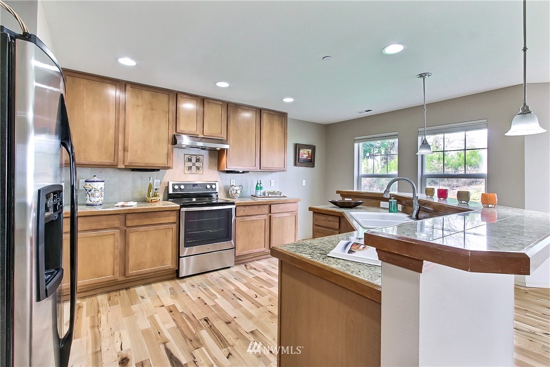 3141 Walker Road DuPont, WA 98327 - Photo 5 of 18 a kitchen with stainless steel appliances granite countertop a stove a sink dishwasher a refrigerator and white cabinets with wooden floor