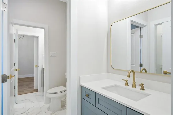 a bathroom with a granite countertop sink a toilet and shower