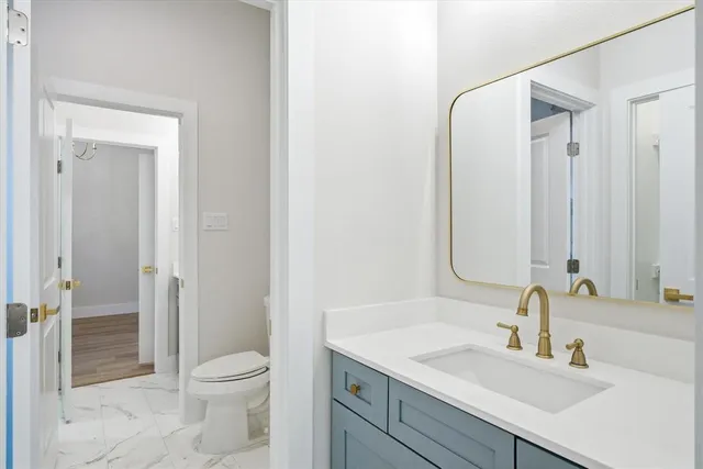 a bathroom with a granite countertop sink a toilet and shower