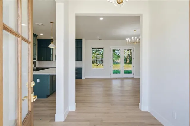 a view of a hallway with wooden floor and a bathroom