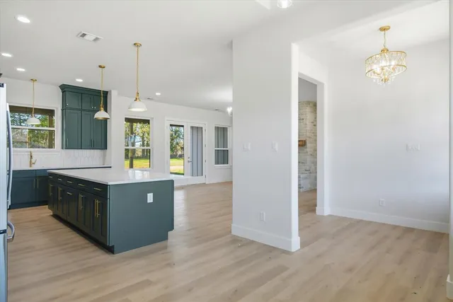 a kitchen with stainless steel appliances granite countertop a refrigerator a sink dishwasher a kitchen island and wooden floor