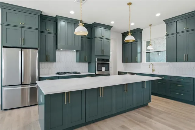 a large kitchen with stainless steel appliances a large counter top space cabinets and wooden floor