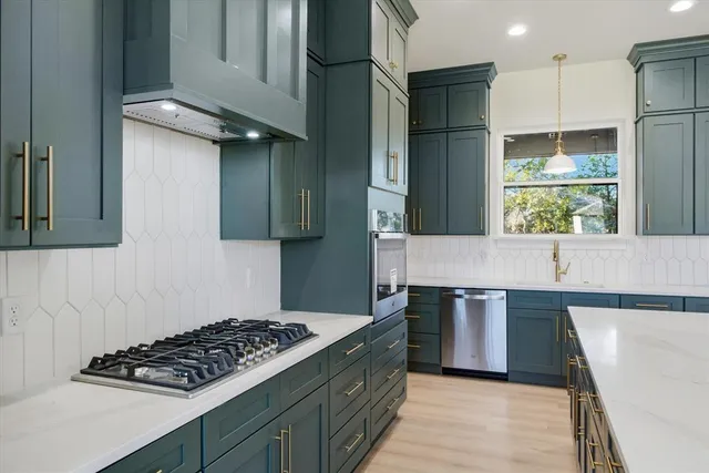 a kitchen with stainless steel appliances granite countertop a stove a refrigerator and a sink