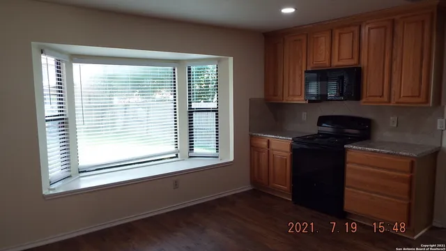 a kitchen with granite countertop wooden cabinets and a stove