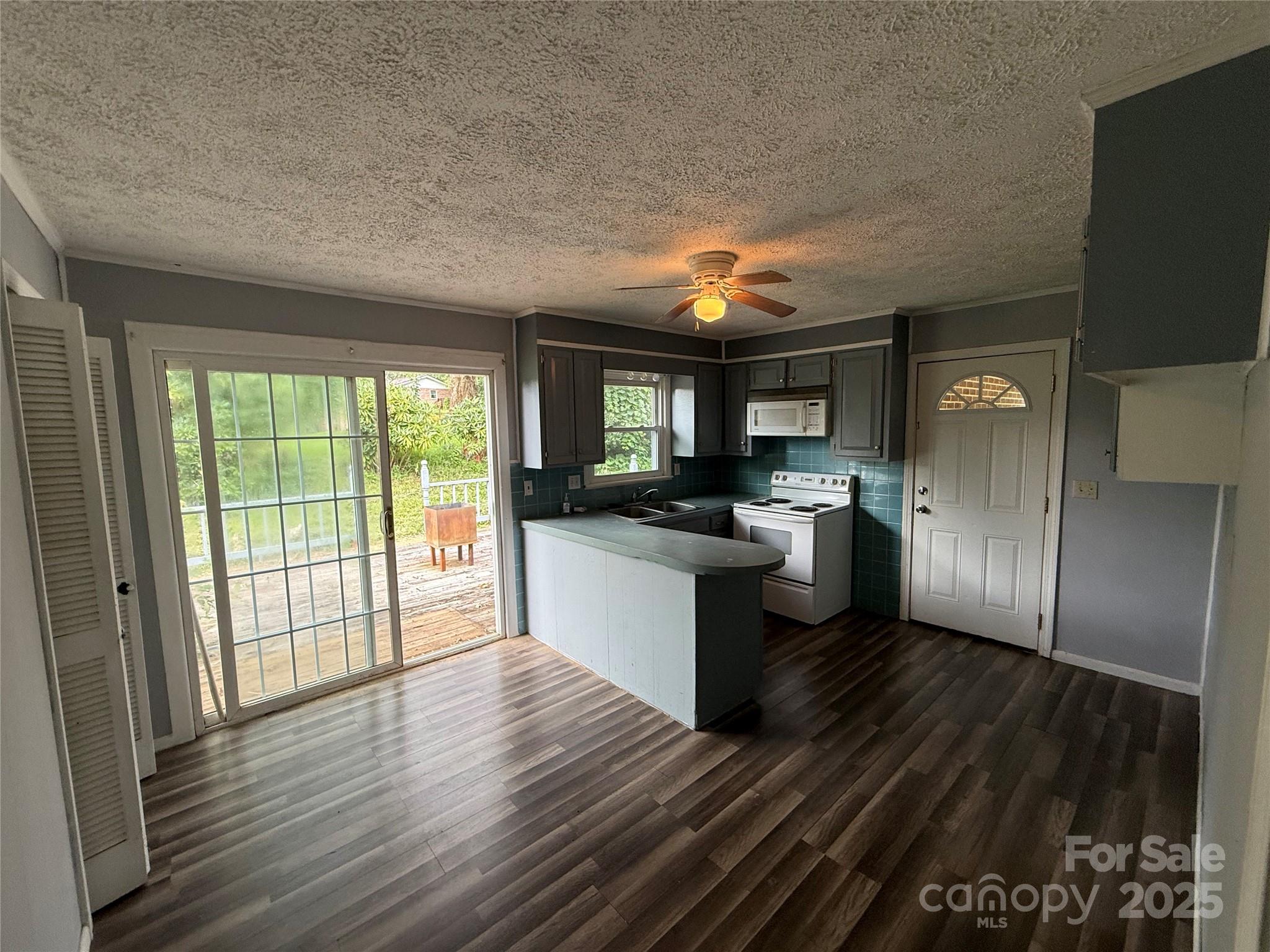 183 Maple Road Spruce Pine, NC 28777 - Photo 18 of 30 a kitchen with stainless steel appliances granite countertop a refrigerator a sink dishwasher a stove and white countertops with wooden floor
