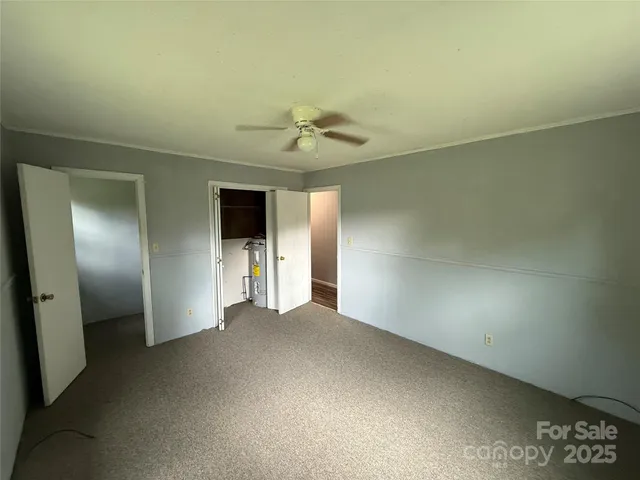 an empty room with a chandelier fan and windows