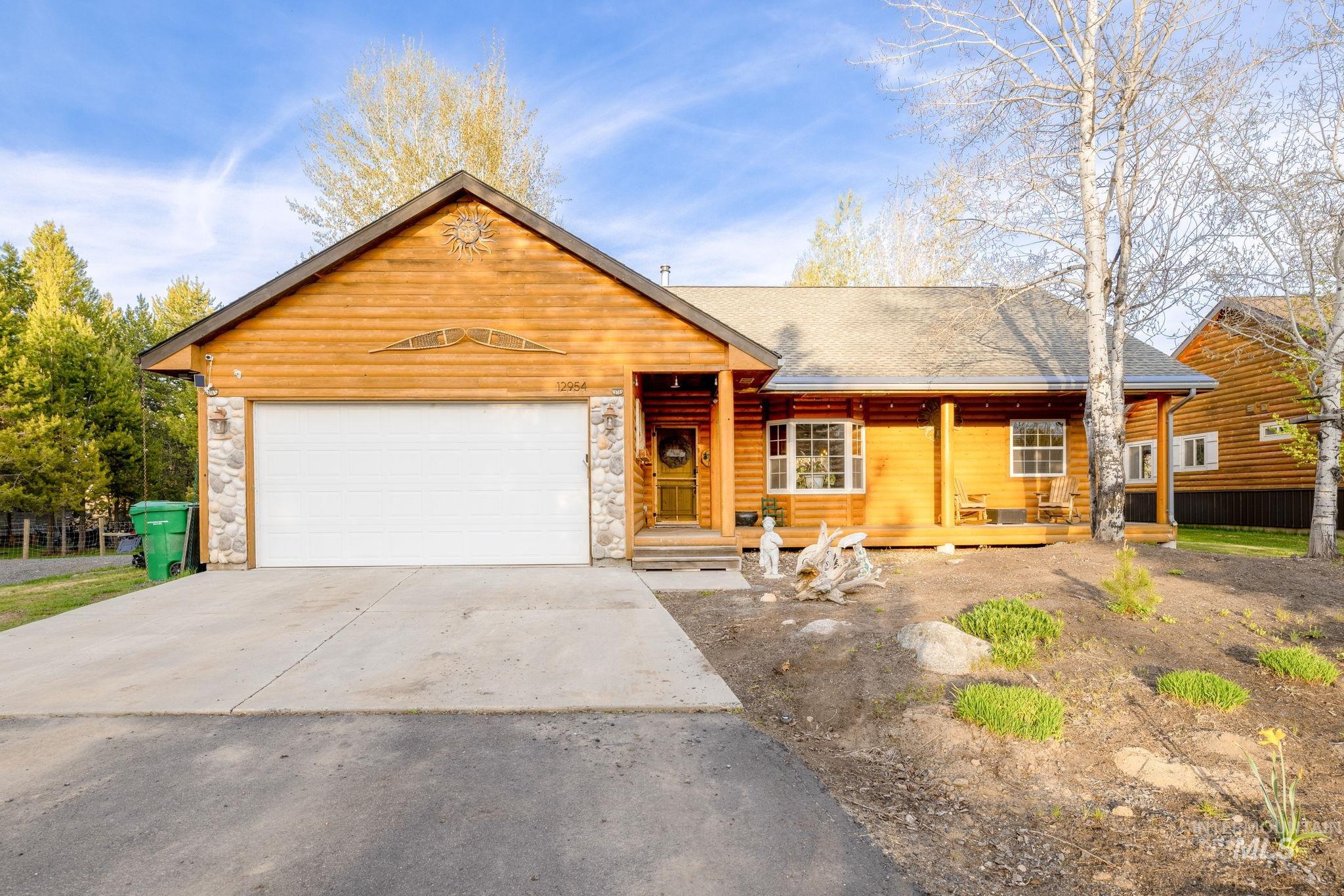 12954 Upland Road Donnelly, ID 83615 - Photo 1 of 41 View of front of house with stone siding, a garage, driveway, covered porch, and a shingled roof