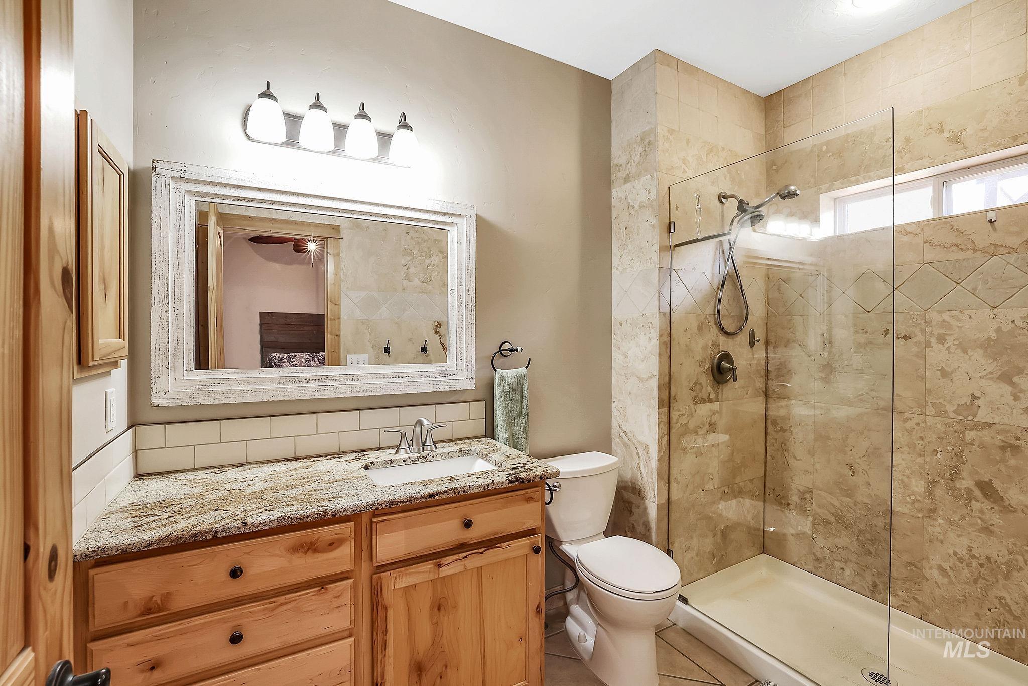12954 Upland Road Donnelly, ID 83615 - Photo 18 of 41 Full bathroom featuring backsplash, vanity, and a shower stall