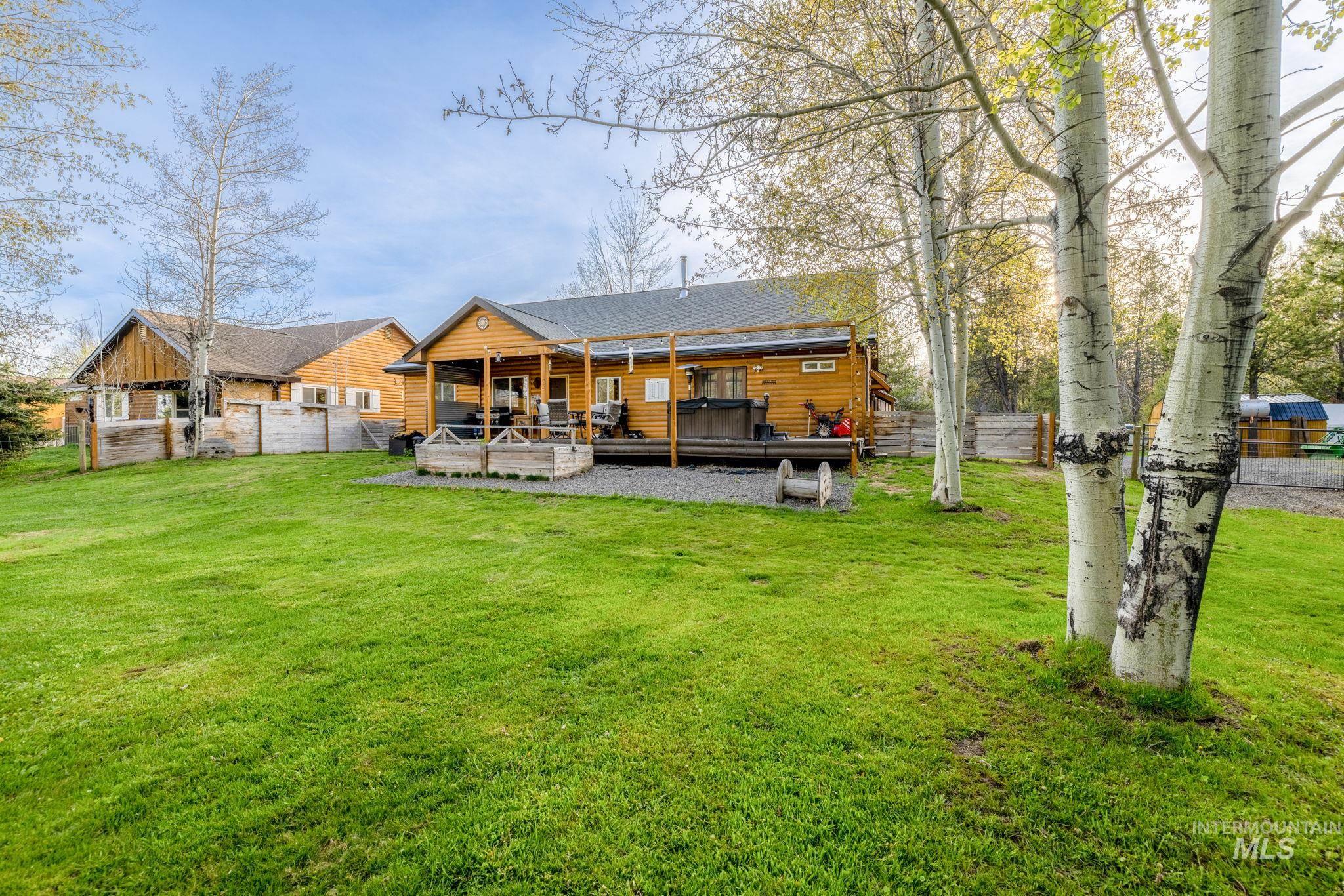 12954 Upland Road Donnelly, ID 83615 - Photo 30 of 41 Back of house featuring a wooden deck, a jacuzzi, and log veneer siding